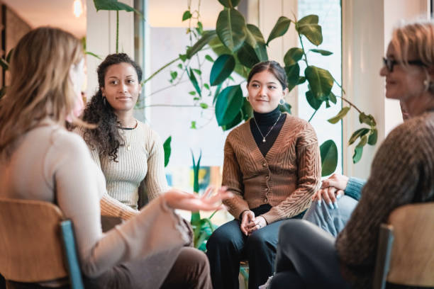 Women participating in a supportive group discussion focused on self-compassion and confidence, surrounded by greenery in a warm, inviting setting.