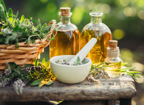 Herbal ingredients and essential oils in bottles, with a mortar and pestle, representing naturopathy services at Balanced Life Therapy.