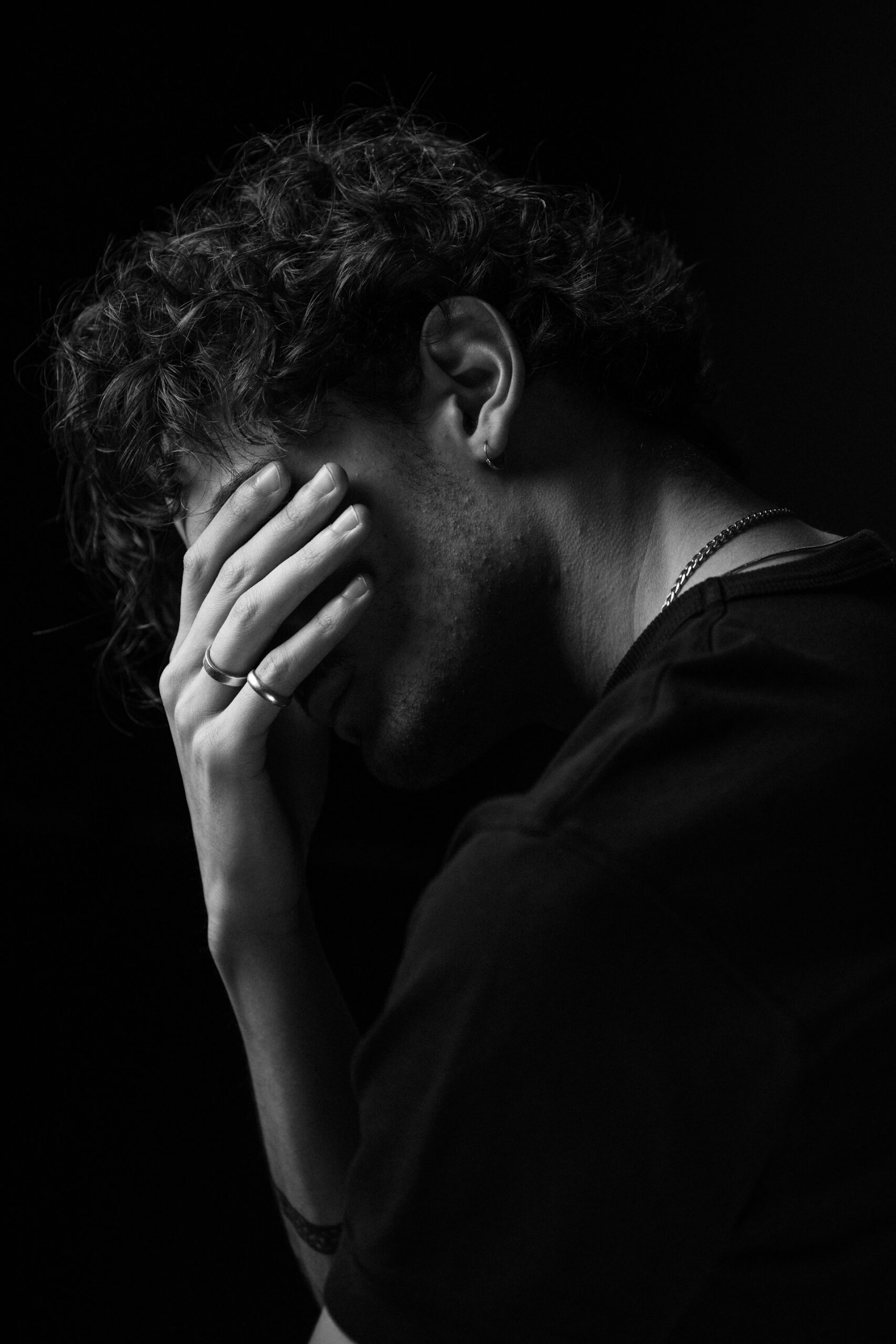Man with hands covering face, illustrating emotional processing and mental health therapy.