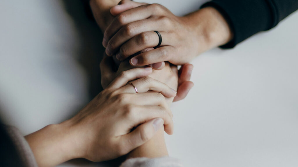 Two people holding hands in support during depression therapy